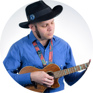 A man in a blue shirt and cowboy hat strums a ukulele