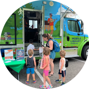 A woman and three children stand in front of the open mobile library