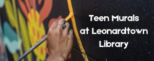 A hand painting a yellow line. Teen Murals at Leonardtown Library