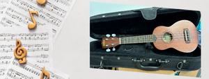 A wooden ukulele propped up inside a black case, with sheet music and gold music notes surrounding it