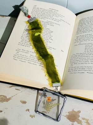 An green bookmark with an acrylic attachment lying over an open book