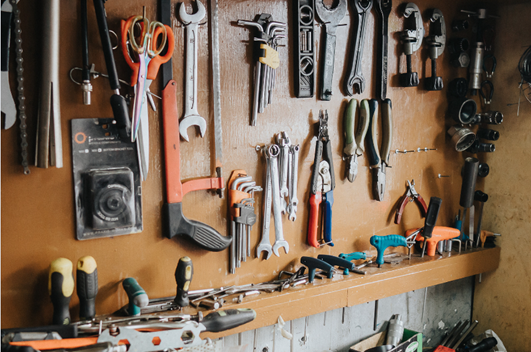 A peg board wall with a variety of tools hanging from it