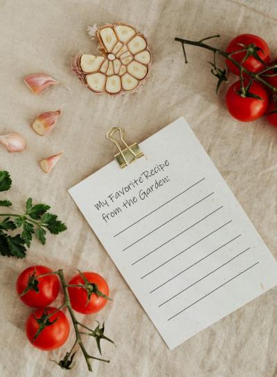 A blank recipe card reading My Favorite Recipe from the Garden surrounded by tomatoes, garlic, and herbs