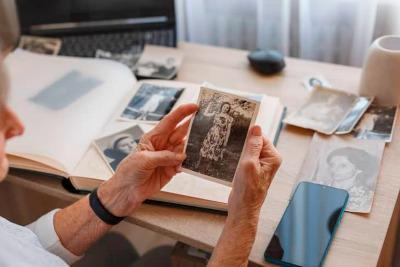 Hands holding an old photograph, with a photo album on the table in the background