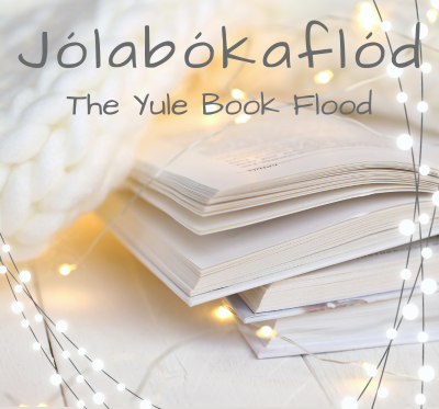 An open book near a cable knit blanket with twinkling lights surrounding them. Jolabokaflod, The Yule Book Flood