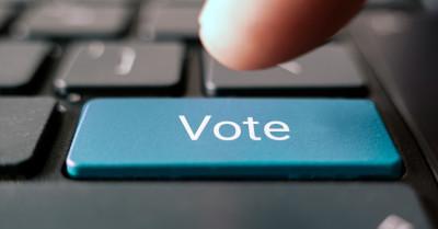 A finger is about to press a blue Vote button on a keyboard